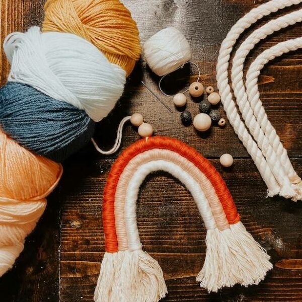 Close-up of a macrame wall hanging being crafted with colored knotted cotton cords.
