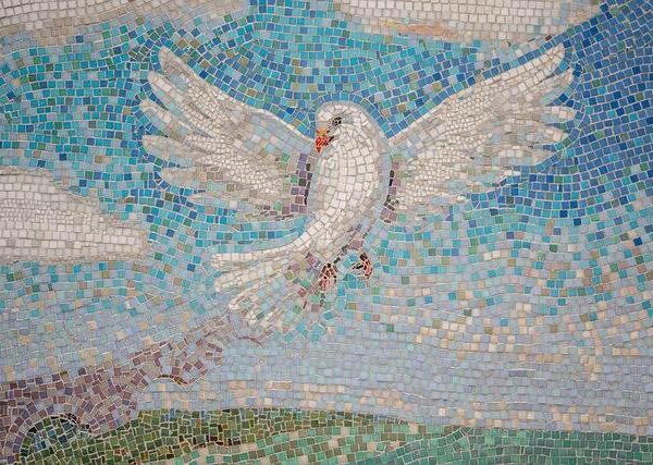 Colorful mosaic tile pattern of a dove being arranged on a wooden surface.
