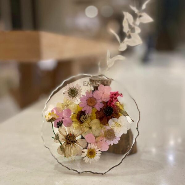 Glossy resin coasters with embedded flowers and pigments created in a resin pouring workshop.